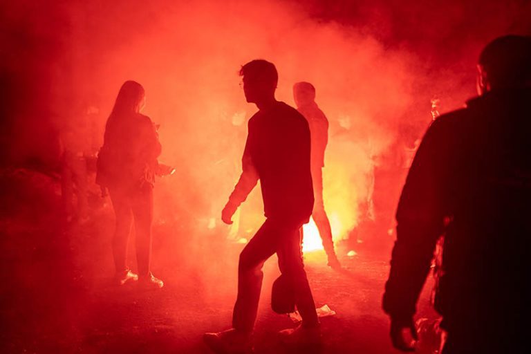 Silhouettes dans la fumée rouge d’une soirée