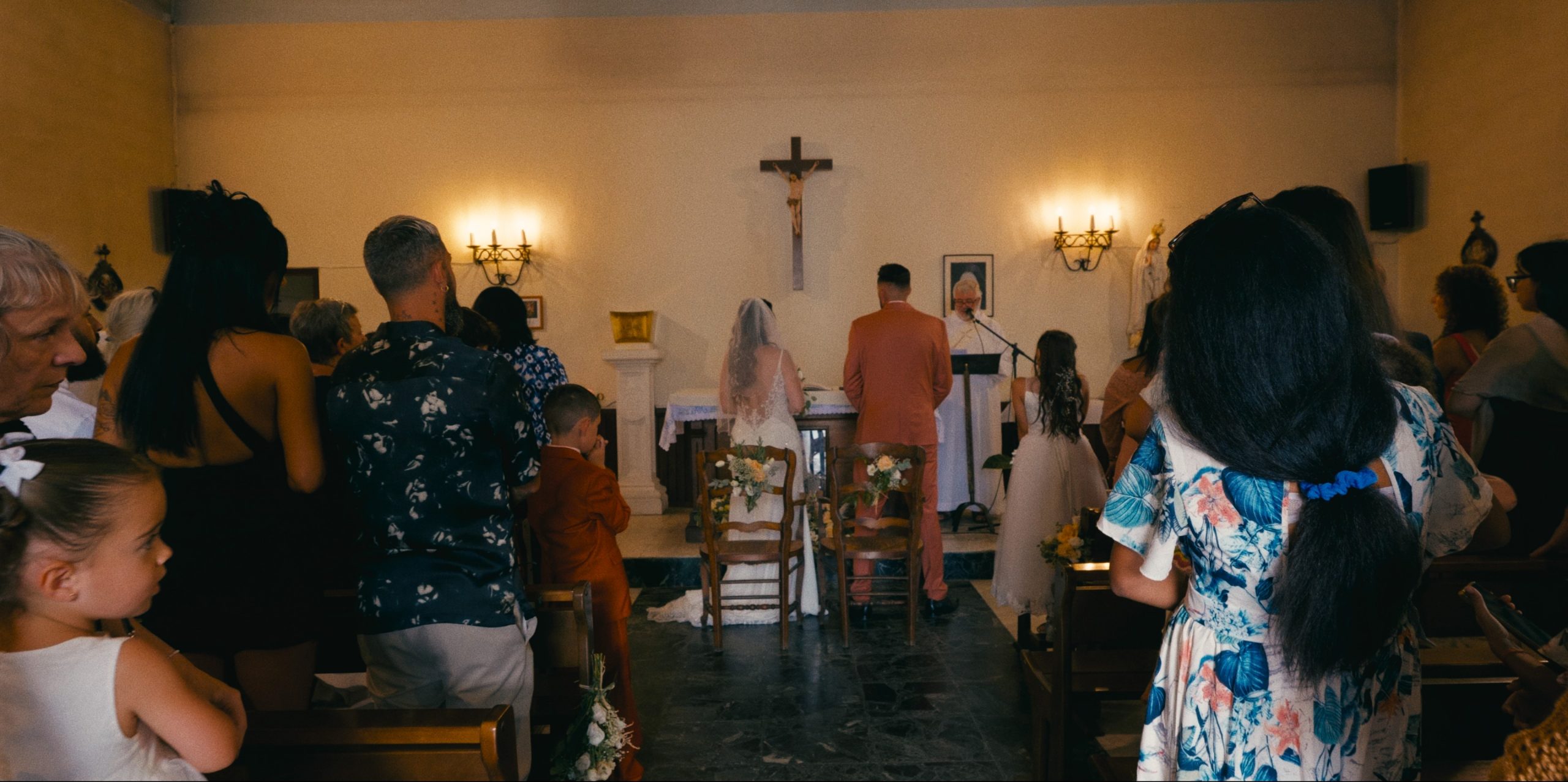 The ceremony in the chapel, guests standing around the couple