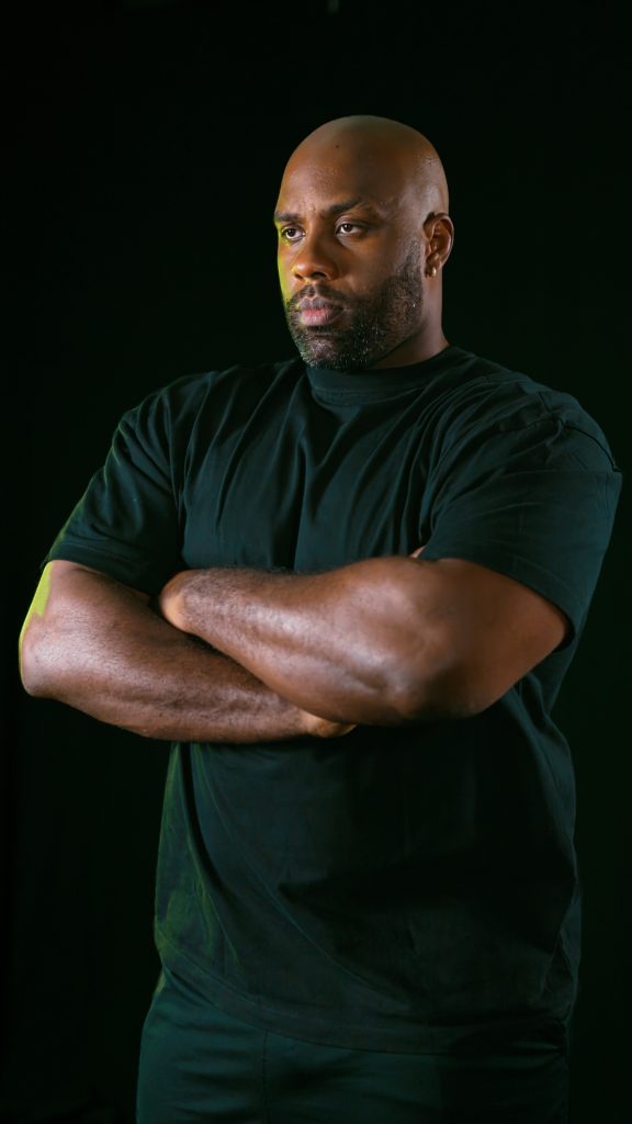 Teddy Riner, arms crossed, looking into the distance