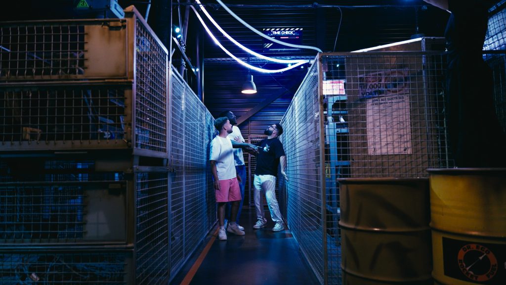Two players in a corridor of metal cages lit by blue neon