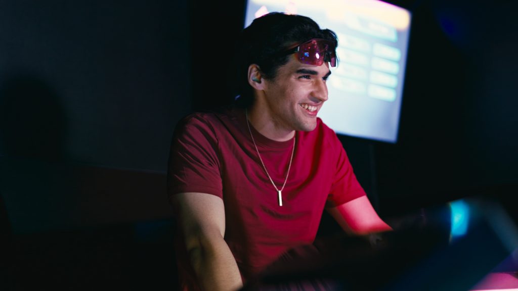 A player in a red T-shirt smiling in front of a game screen
