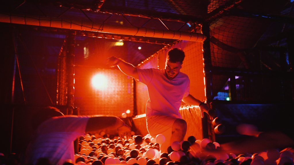 A player jumping into a ball pit lit in orange