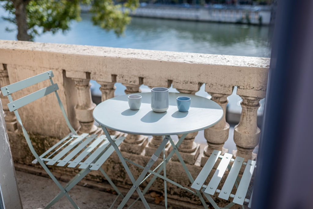 Balcon en pierre avec une petite table de bistrot au-dessus de la Saône
