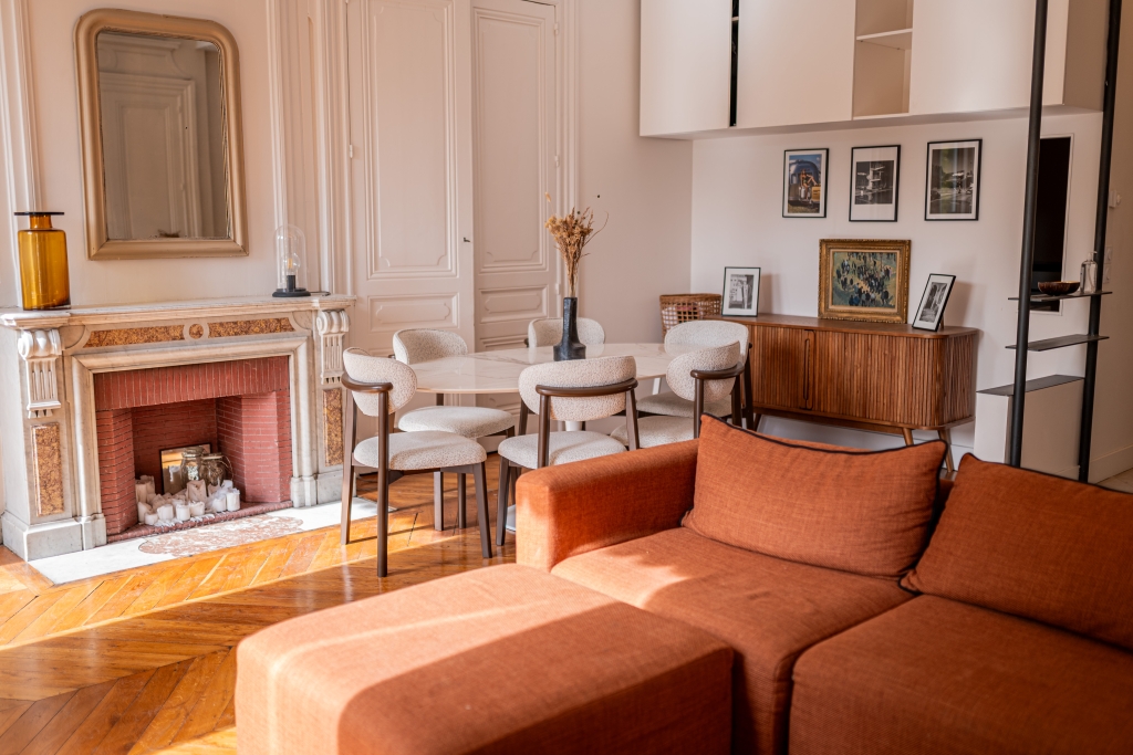 Coin repas et salon avec cheminée, miroir doré et canapé orange