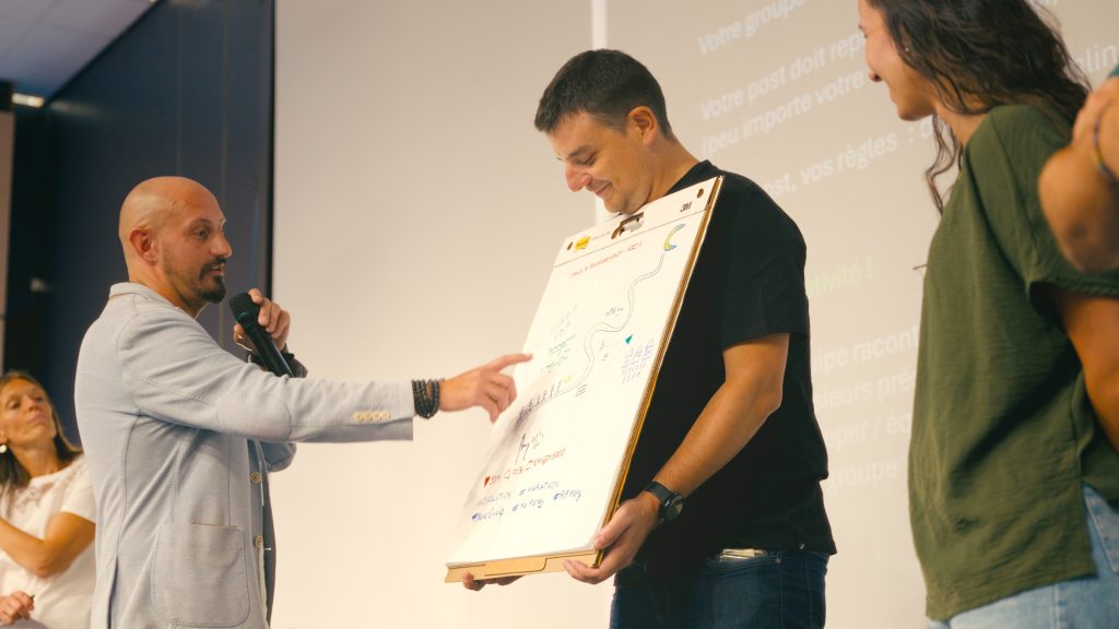 A speaker at the microphone commenting on a flip chart held by a participant